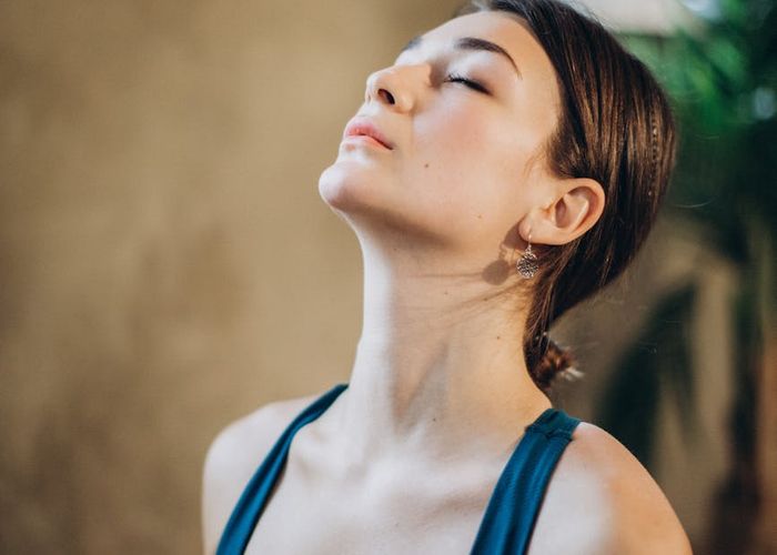 Woman in a graceful yoga pose, meditating in a serene indoor setting.